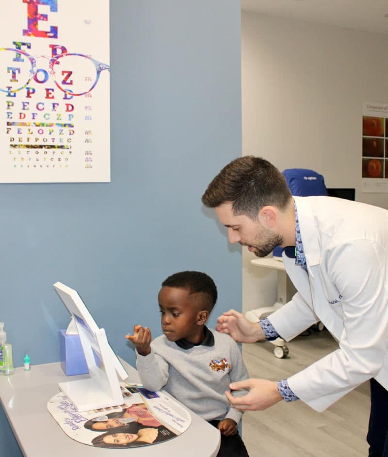Child reading an eye chart with doctor